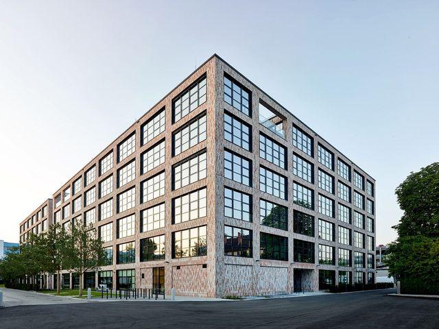 Außenansicht des Neue Siederei Gebäudes mit moderner Fassade und großen Fensterfronten.